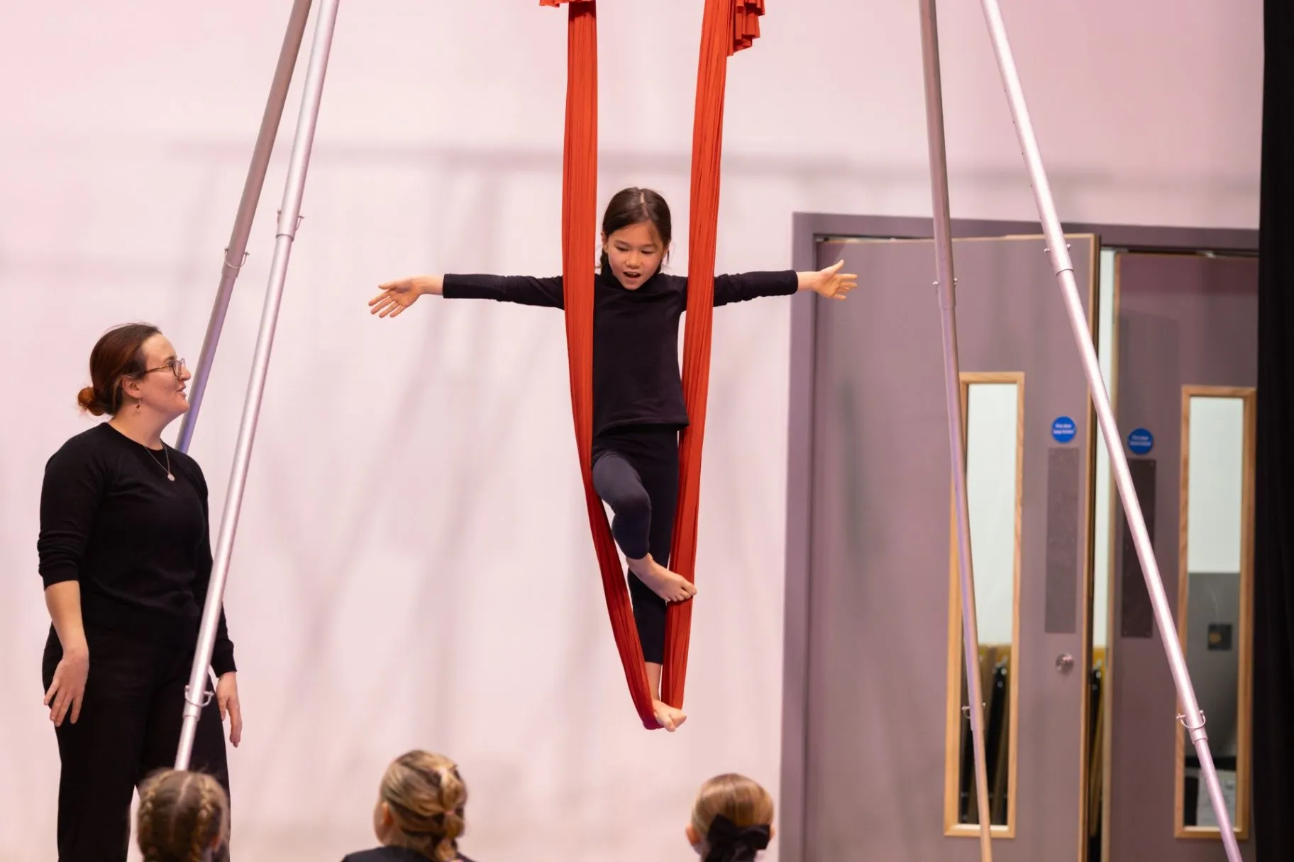 Young person practising aerial silks with a coach in a studio
